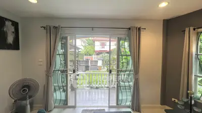 Charming living room with garden view through sliding glass doors, perfect for relaxation.