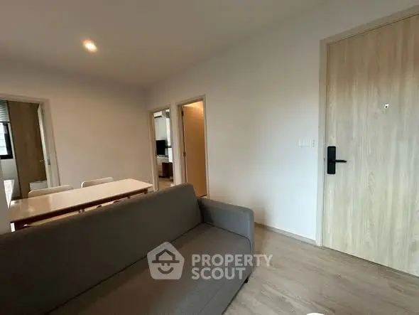 Modern living room with sleek sofa and dining area in open layout apartment.