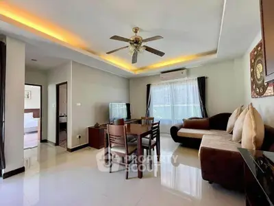 Spacious living room with modern decor, ceiling fan, and natural light, perfect for relaxation and entertainment.