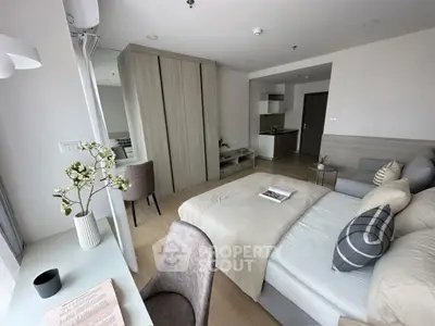 Modern studio apartment with cozy bedroom and compact kitchen area, featuring stylish decor and natural light.