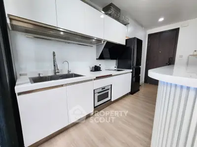 Modern kitchen with sleek white cabinets and built-in appliances in a stylish apartment.