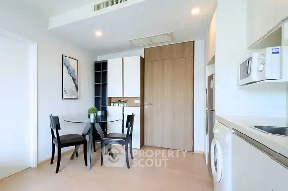 Modern kitchen with dining area, featuring sleek appliances and minimalist design.