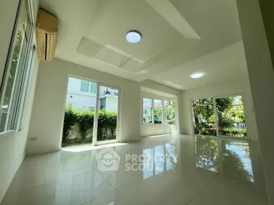 Spacious sunlit living room with large windows and garden view, perfect for modern living.