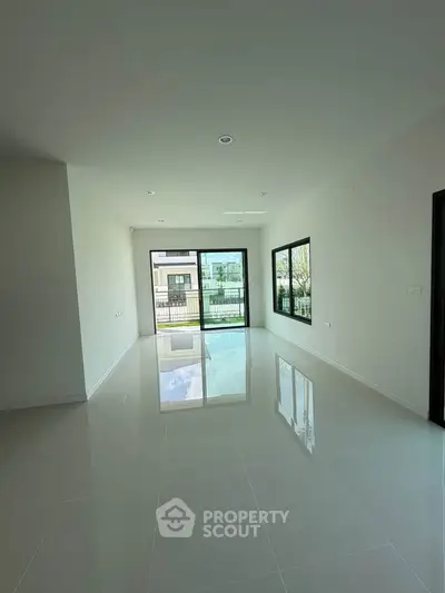 Spacious modern living room with large windows and glossy floors