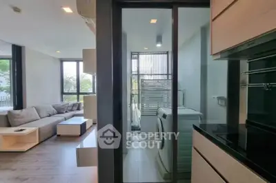 Modern apartment with sleek living room and laundry area featuring a washing machine.