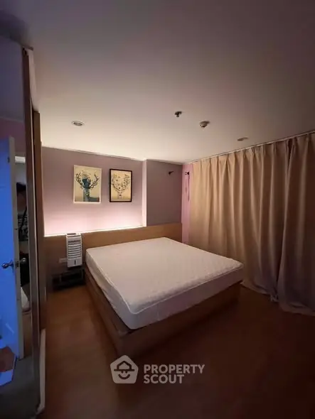 Cozy bedroom with warm lighting and elegant decor, featuring a comfortable bed and stylish artwork.