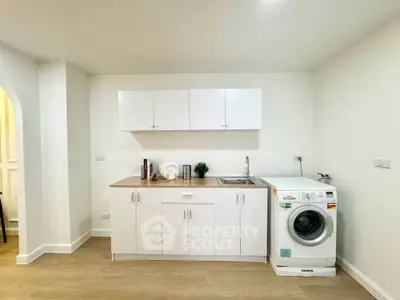 Modern kitchen with washing machine and sleek white cabinets