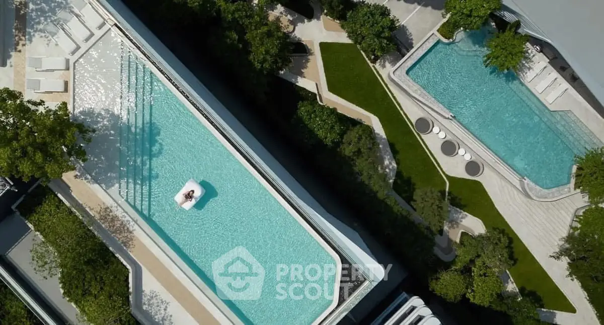 Luxurious aerial view of modern swimming pools surrounded by lush greenery in a high-end residential complex.