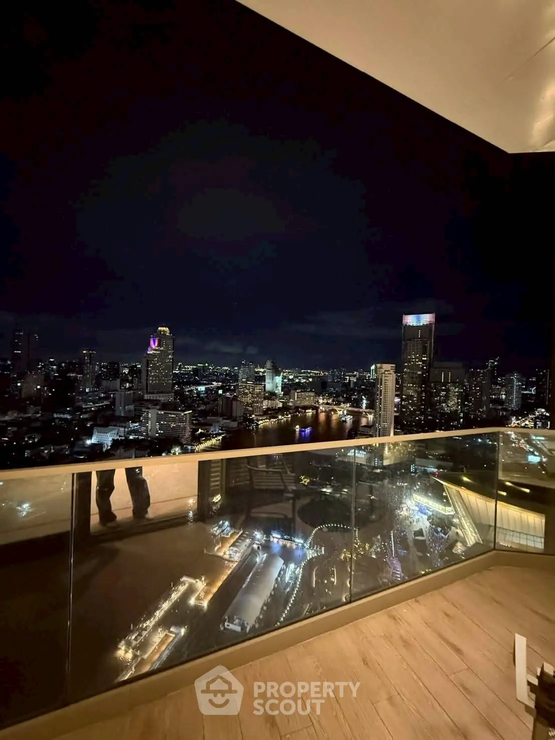 Stunning cityscape view from a high-rise balcony at night, showcasing vibrant city lights.