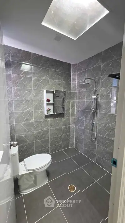 Modern bathroom with sleek gray tiles and overhead shower in a contemporary home.