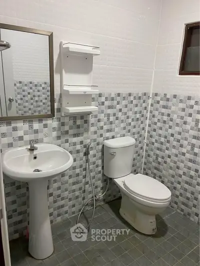 Modern bathroom with pedestal sink and tiled walls in a stylish real estate property.