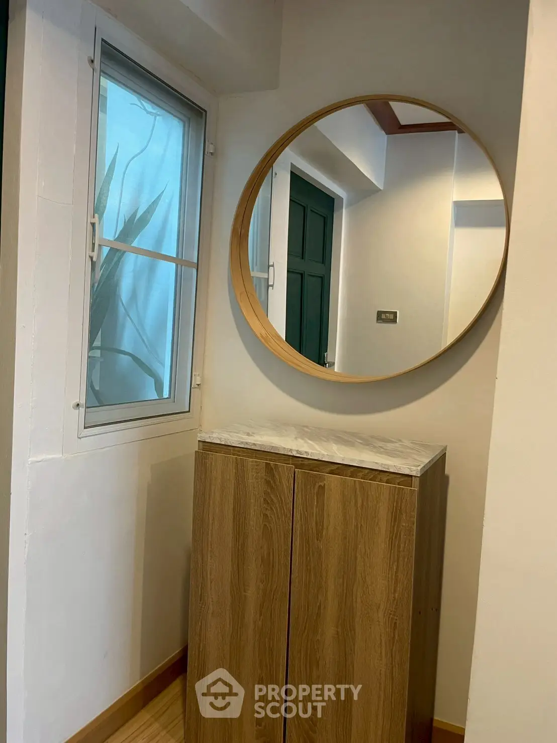 Stylish entryway with round mirror and wooden cabinet