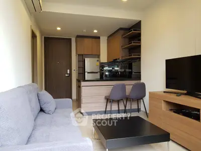 Modern living room with open kitchen, sleek furniture, and cozy ambiance in a stylish apartment.