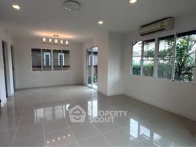 Spacious living room with large windows and modern lighting in a bright home.