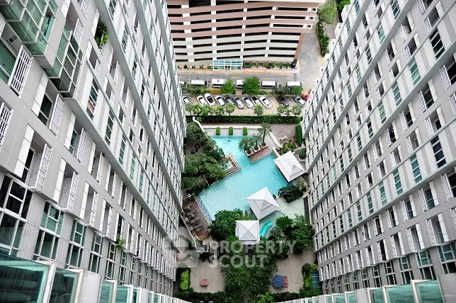 Stunning aerial view of modern apartment complex with central pool and lush greenery.