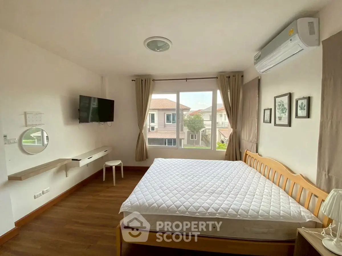 Bright bedroom with large window, wooden bed, and wall-mounted TV in modern home.