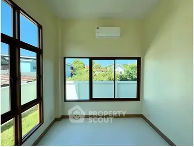 Bright room with large windows and air conditioning, overlooking a garden view.