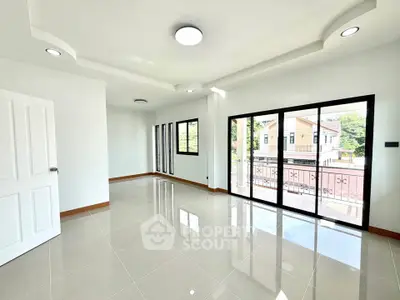 Spacious modern living room with large windows and balcony access, offering abundant natural light and sleek tile flooring.