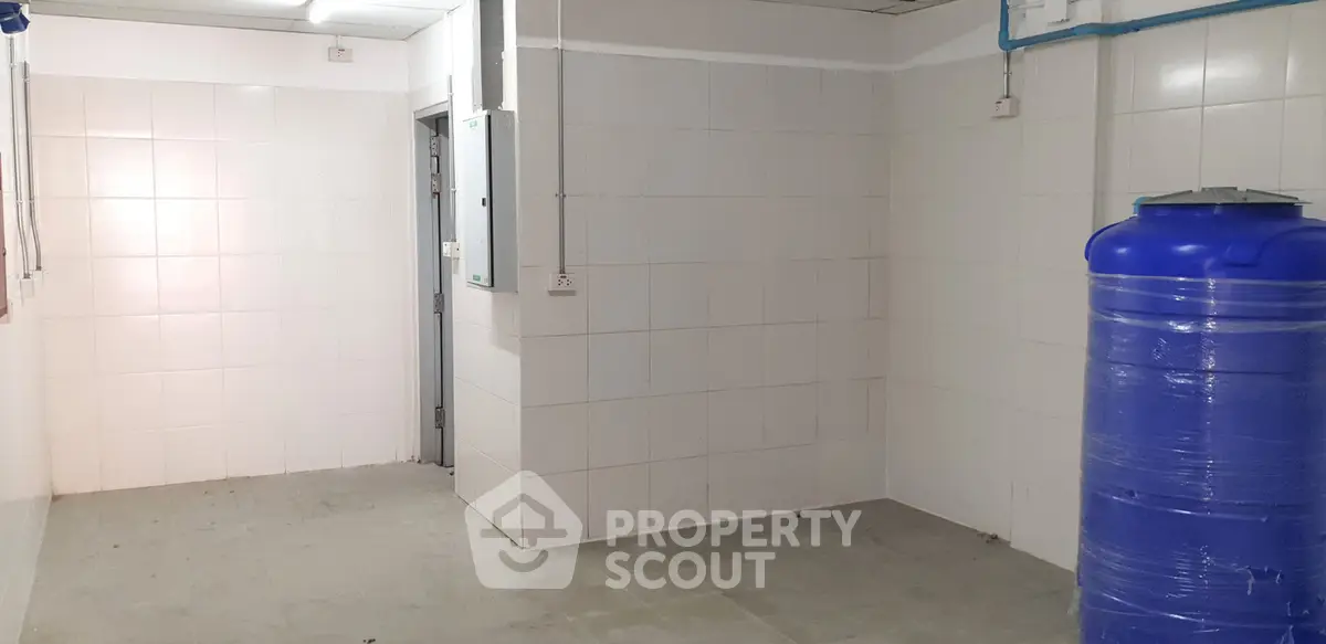 Spacious tiled utility room with water tank, ideal for storage or laundry setup.