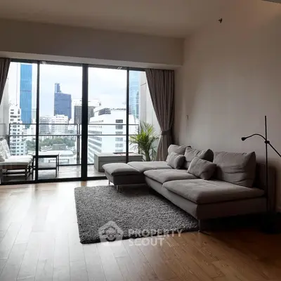 Spacious living room with modern sofa and city view from large windows.