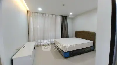 Spacious bedroom with large window and modern furnishings in a stylish apartment.