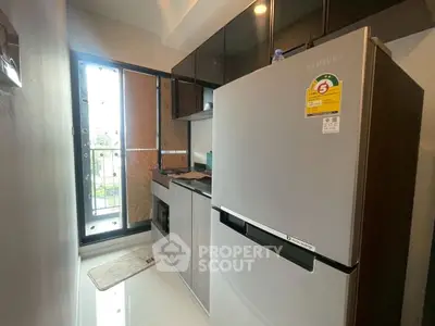 Modern kitchen with stainless steel fridge and sleek cabinetry in compact layout