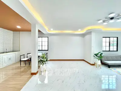 Spacious modern living room with stylish ceiling lights and open layout kitchen.