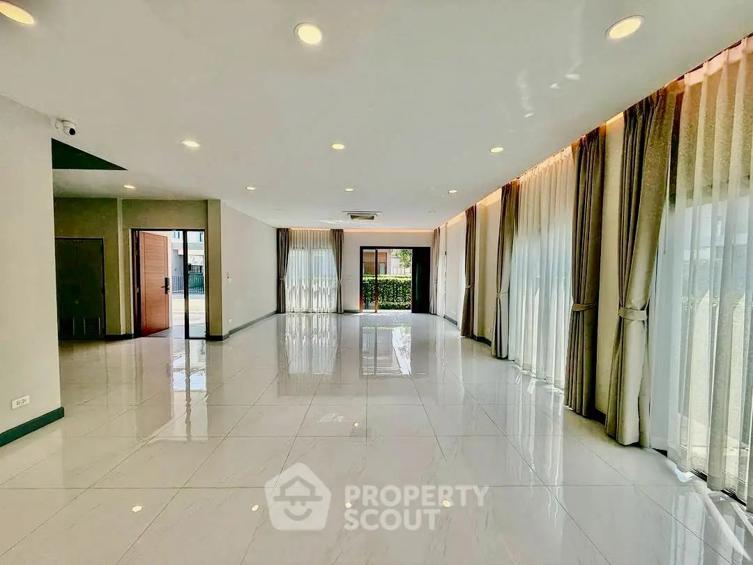 Spacious modern living room with large windows and elegant curtains