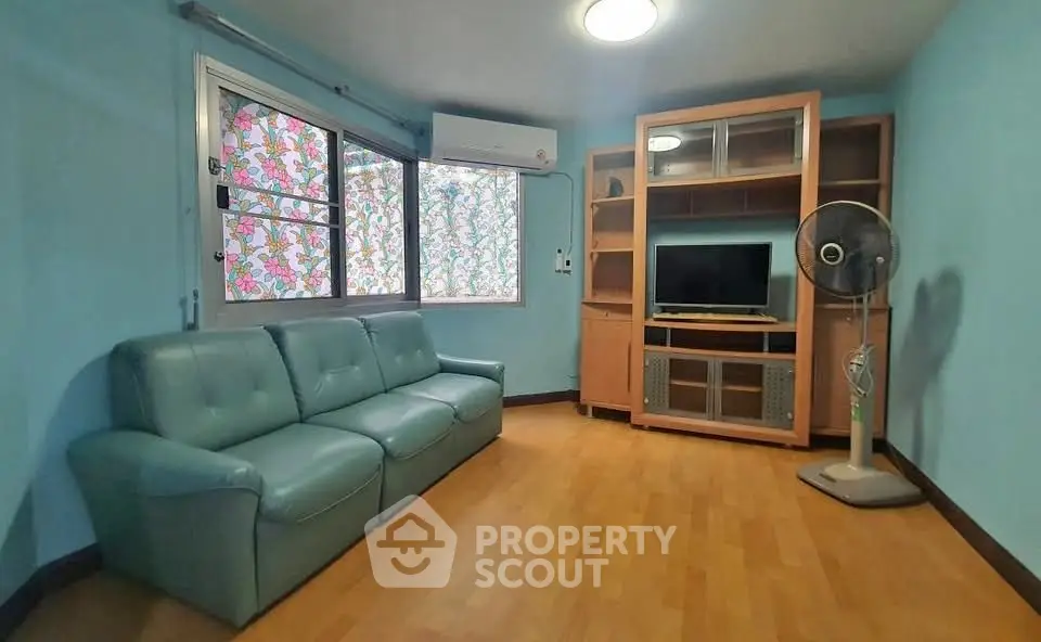 Cozy living room with teal sofa and entertainment center, ideal for relaxation.