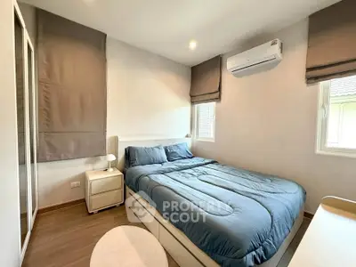 Cozy bedroom with modern decor and natural light, featuring a comfortable bed and air conditioning.