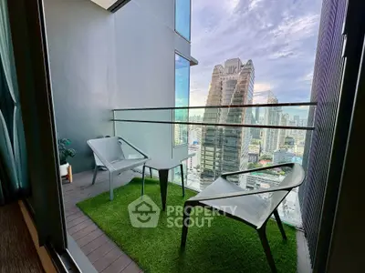 Modern balcony with city view, featuring stylish chairs and artificial grass flooring.