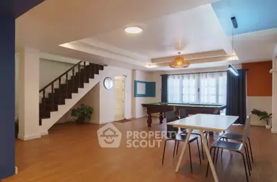 Spacious modern living room with pool table and dining area, featuring stylish lighting and wooden flooring.