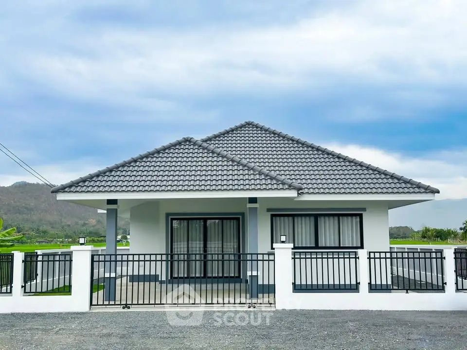 Charming single-story house with modern design and mountain views, featuring a spacious front yard and secure fencing.