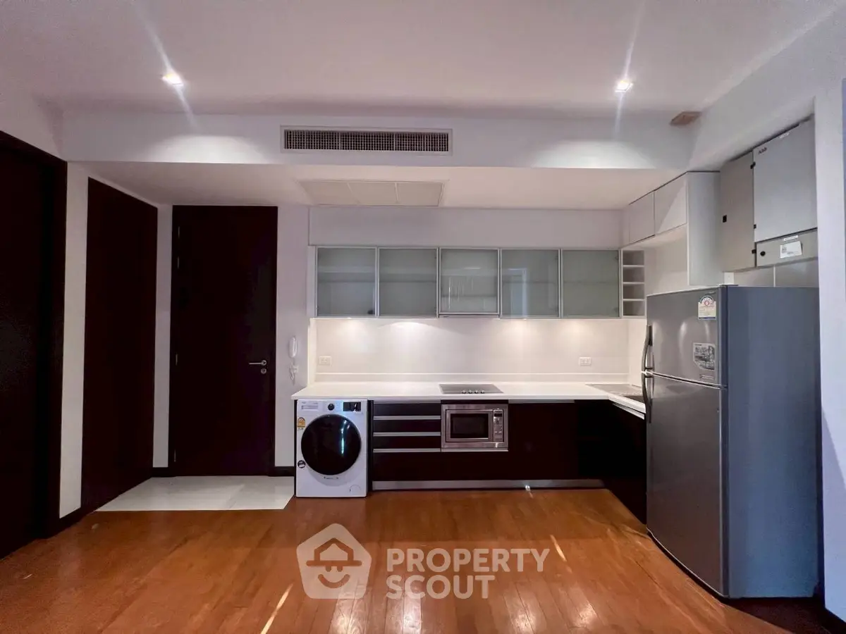 Modern kitchen with sleek appliances and wooden flooring in a stylish apartment.