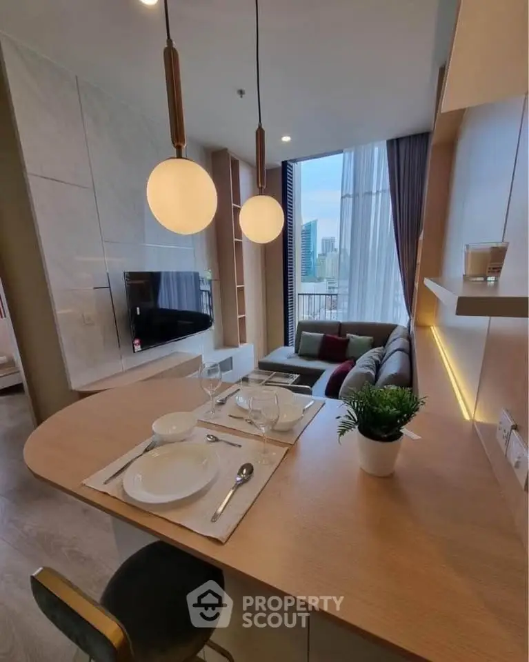 Modern open-layout living room with dining area and city view, featuring stylish lighting and cozy seating.