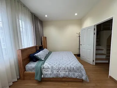 Spacious bedroom with modern decor and wooden flooring, featuring a cozy bed and ample natural light.