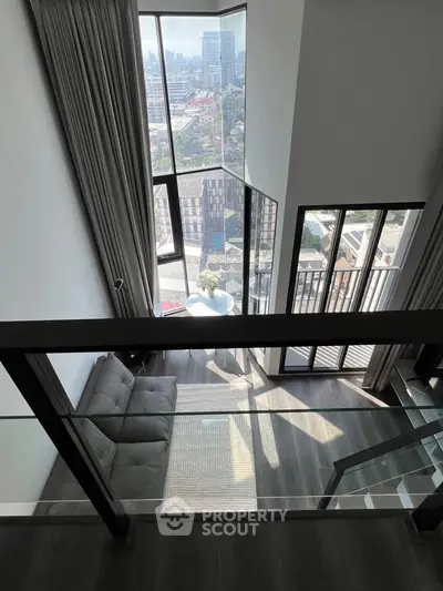 Stunning duplex apartment with floor-to-ceiling windows and city view, featuring a cozy living area and balcony.