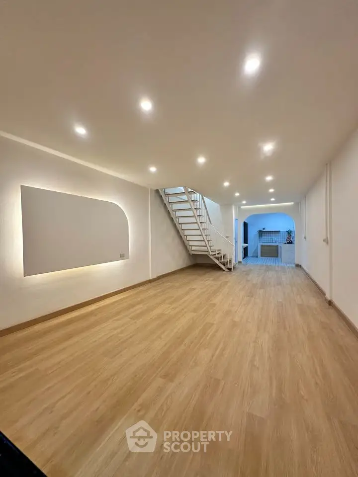 Spacious open-plan living area with modern staircase and wooden flooring, perfect for contemporary living.
