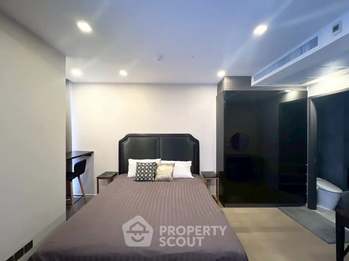 Modern bedroom with sleek design and integrated bathroom, featuring stylish furniture and ambient lighting.