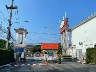 Secure gated entrance with guardhouse and barriers in a residential complex.