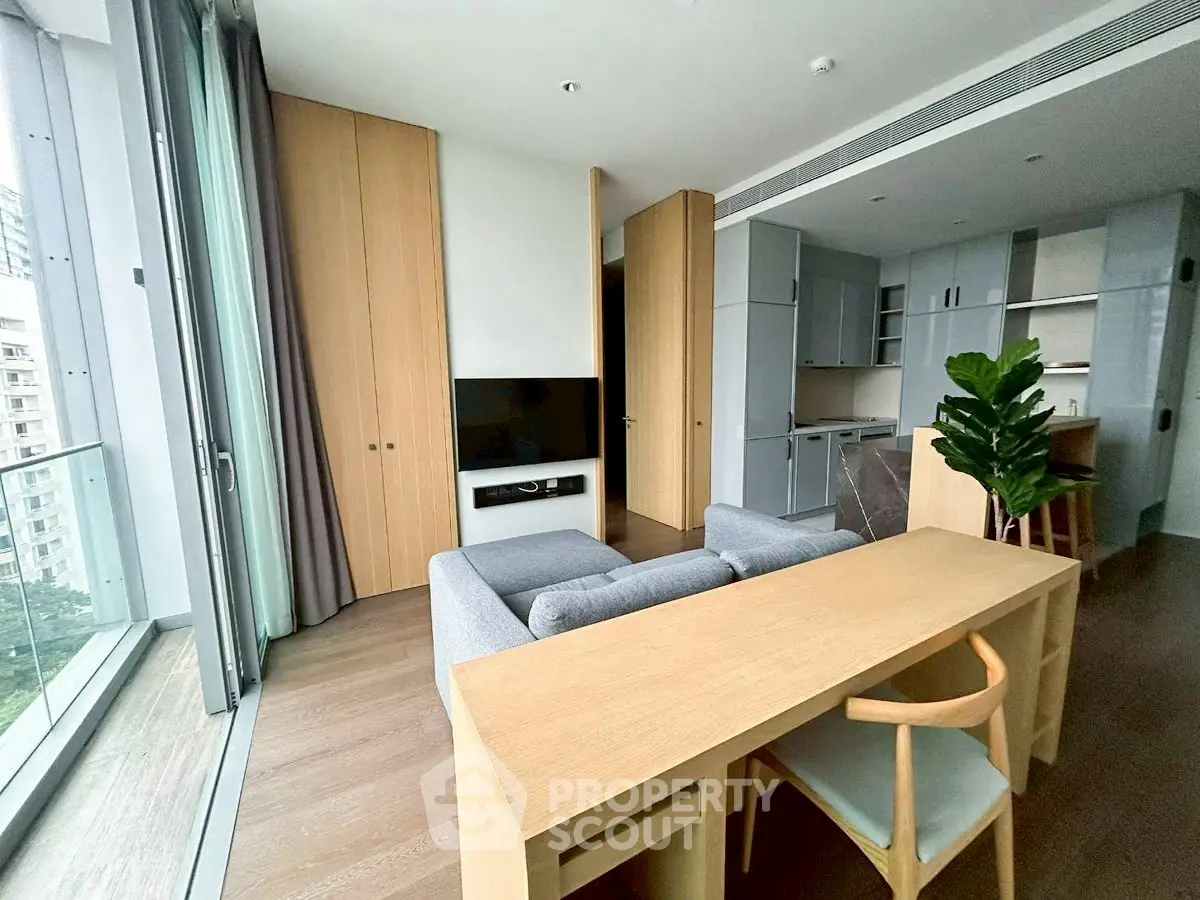 Modern living room with open kitchen and balcony view in a stylish apartment.