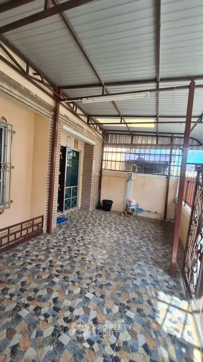 Spacious covered patio with tiled flooring and metal railings, perfect for outdoor relaxation.