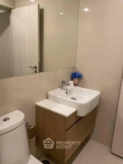 Modern bathroom with sleek vanity and large mirror in contemporary apartment.