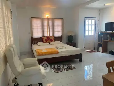 Spacious bedroom with cozy furnishings and natural light, perfect for relaxation.