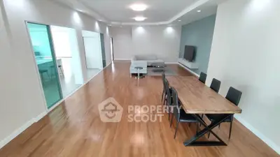 Spacious modern living room with wooden flooring, dining area, and sleek furniture.