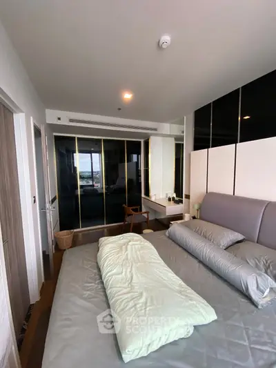 Modern bedroom with sleek design and large mirrored wardrobe, offering a spacious and stylish living space.