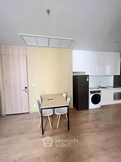 Modern kitchen with dining area, featuring sleek appliances and minimalist design.