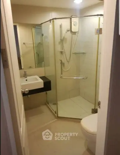 Compact modern bathroom with glass shower enclosure and sleek fixtures.