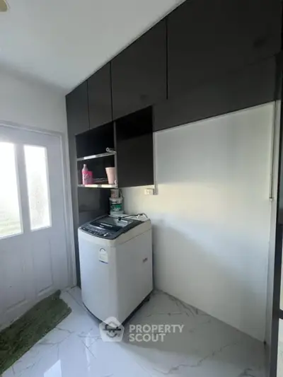 Modern laundry area with sleek black cabinets and washing machine