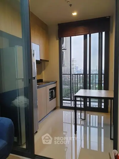 Modern kitchen with sleek cabinetry and city view from balcony in high-rise apartment.
